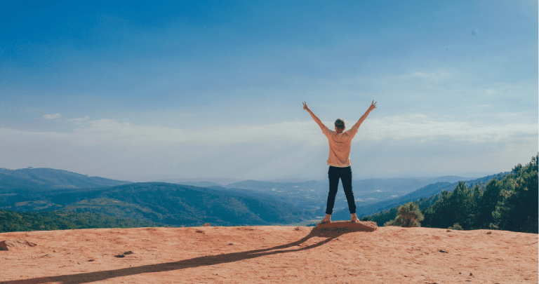 woman celebrating achievement at the top of a hill